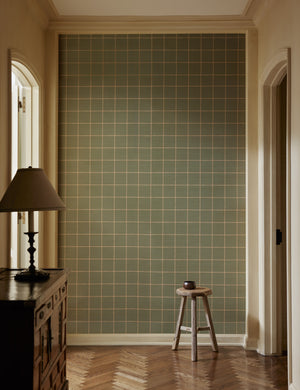 A hallway with a stool and sideboard cabinet featuring Beddow Grid Wallpaper by Jake Arnold