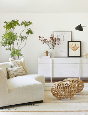The Iconic Stripe Rug lays in a living room with a woven coffee table, an ivory sofa, and a white sideboard
