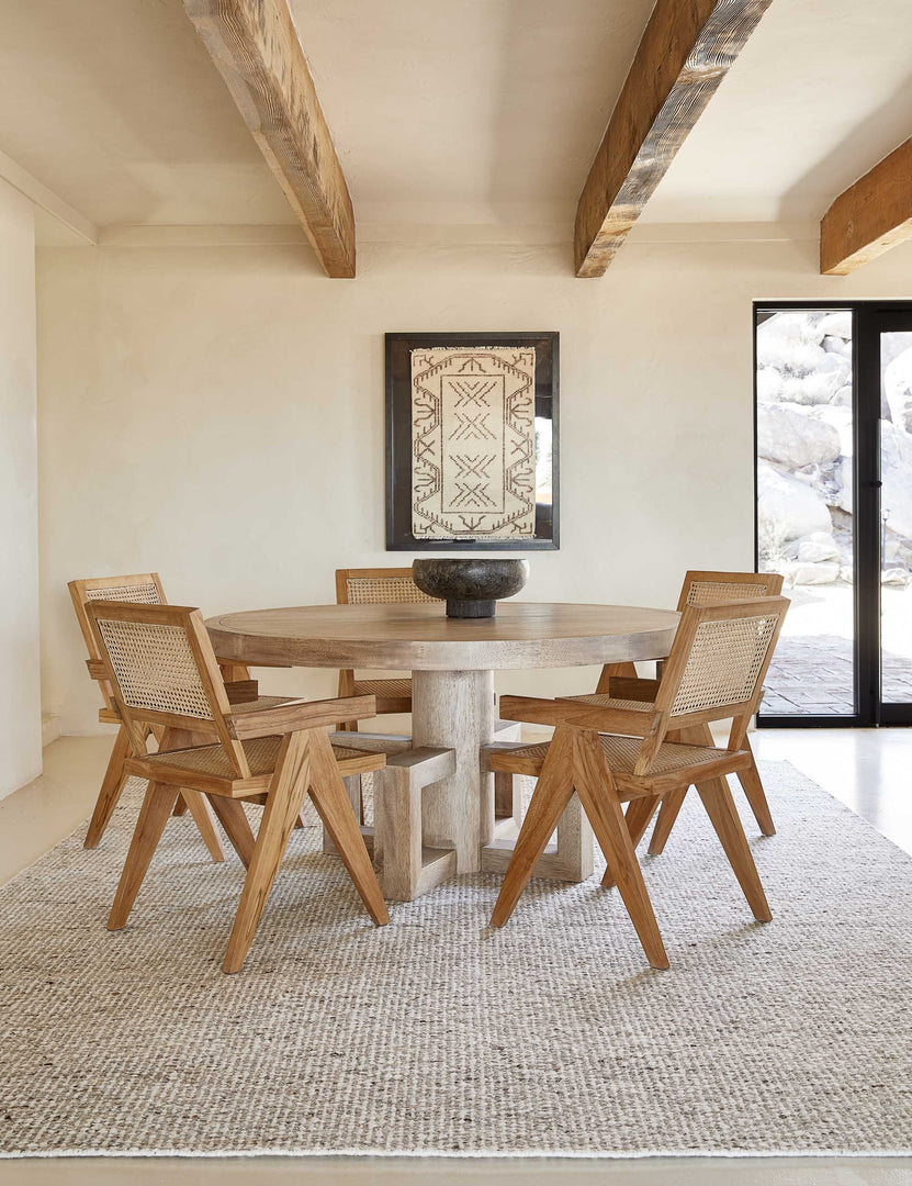 #color::neutral #size::10--x-14- #size::2-6--x-8- #size::6--x-9- #size::8--x-10- #size::9--x-12- | The Taos neutral light brown wool blend area rug lays under a round light wood dining table surrounded by five wood and cane arm chairs.