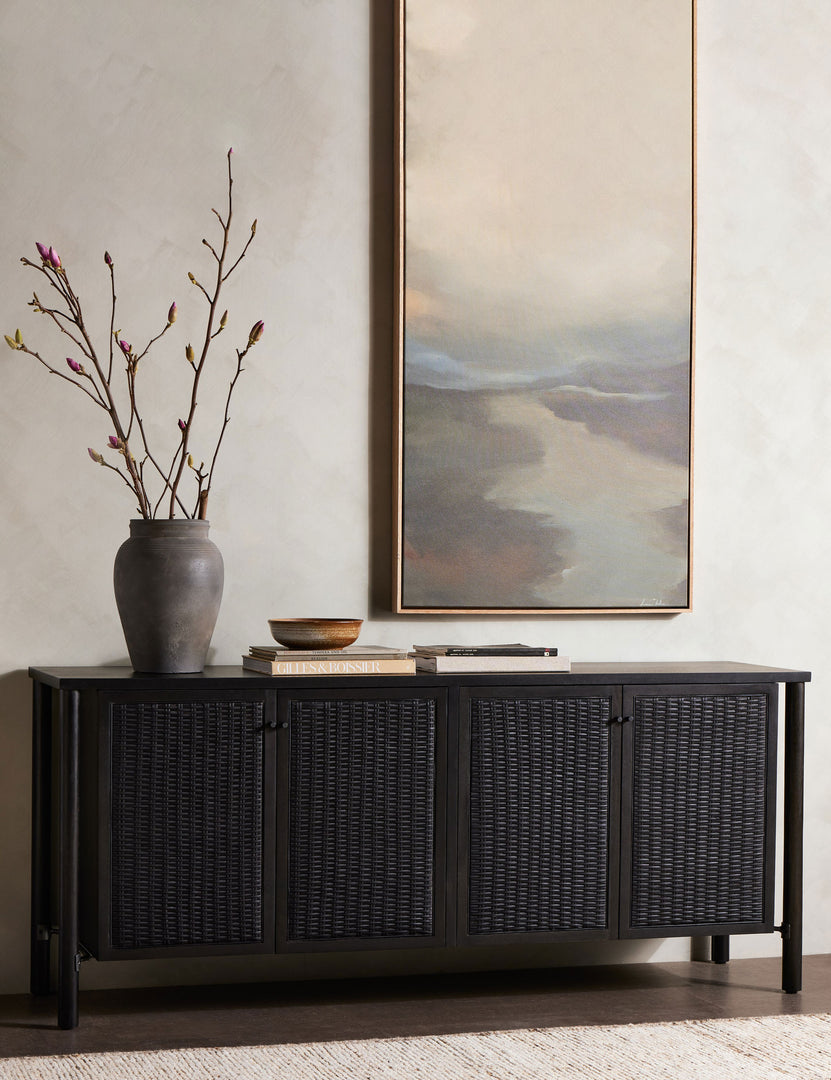#color::black | The Isaura black cane-paneled sideboard cabinet styled with a grey vase and a large canvas wall art piece.