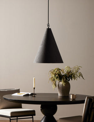 Ashwin sleek cone pendant light in black hanging over a dining table.