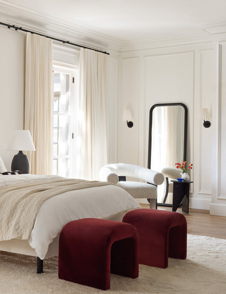 #color::paprika | Two Paprika Velvet Tate Stools sit at the end of a bed with an arched headboard atop a plush rug
