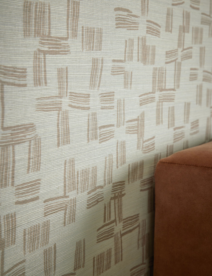 #color::ivory | Angled view of the Crossmarks Grasscloth Wallpaper by Élan Byrd on a wall.