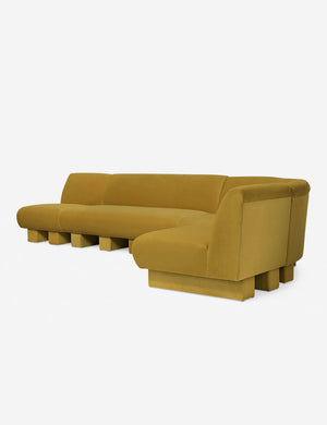 Angled view of the Lena right-facing yellow velvet sectional sofa with upholstered beam legs.