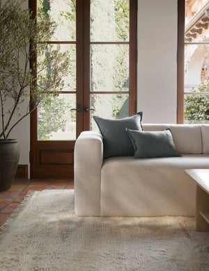 The arlo Dusty Blue flax linen pillow in its lumber and square sizes sit together on a natural linen sofa in a room with tall french doors