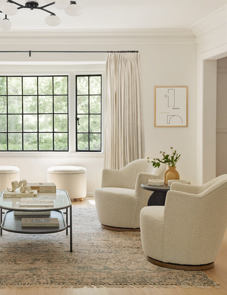 #color::natural-boucle | An ivory sofa sits across from two natural boucle Margie rounded swivel chairs atop an orange Arches area rug.