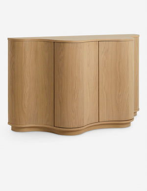 Angled view of the Cora half-moon, wavy light-wood sideboard