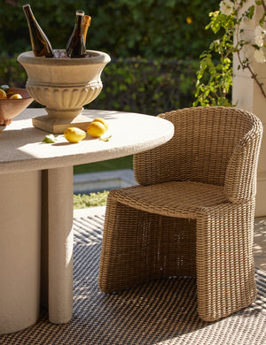 Mettam modern wicker outdoor dining chair styled by a oval outdoor dining table.