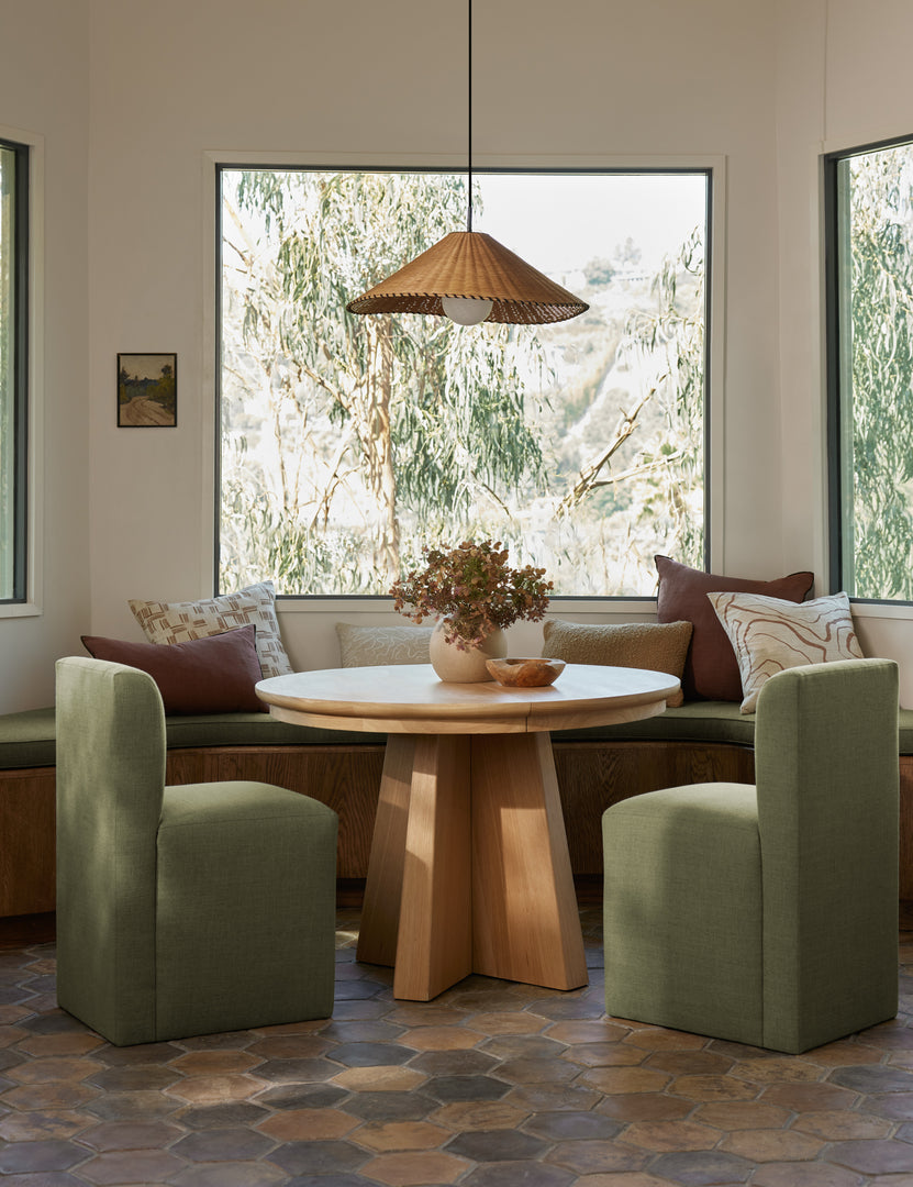 #color::natural #size::25-dia | Terrene Woven Rattan Pendant by Elan Byrd hanging above a dining table.