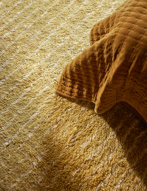 Close up of the Bhari thick organic design hand-knotted wool rug underneath a bed.