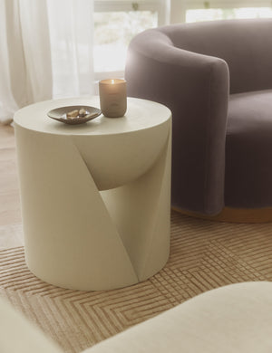Amaya round sculptural cement side table styled with a purple velvet accent chair.