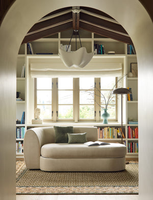 A chaise sitting a top the Manca traditional geometric motif hand-knotted wool rug.