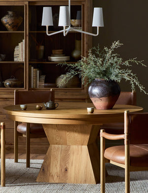 A dining room featuring the Hermoza sculptural round pedestal extendable dining table and leather upholstered dining chairs.