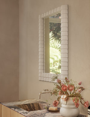 Munro white sculptural modern wall mirror hung above a bathroom sink.