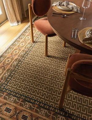 The Manca traditional geometric motif hand-knotted wool rug under a dining room table and chairs.