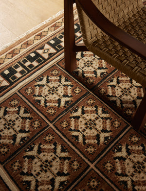 The Ovidi heritage motif hand-knotted wool rug under an accent chair.