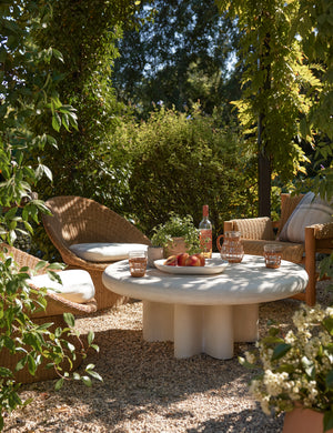 Ferran sculptural wicker outdoor accent chair styled with a round coffee table in an outdoor lounge area.
