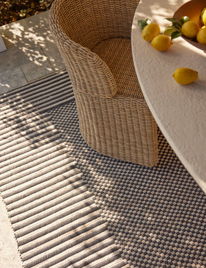 Wicker dining chair styled with the Lavinia handwoven high contrast outdoor rug.