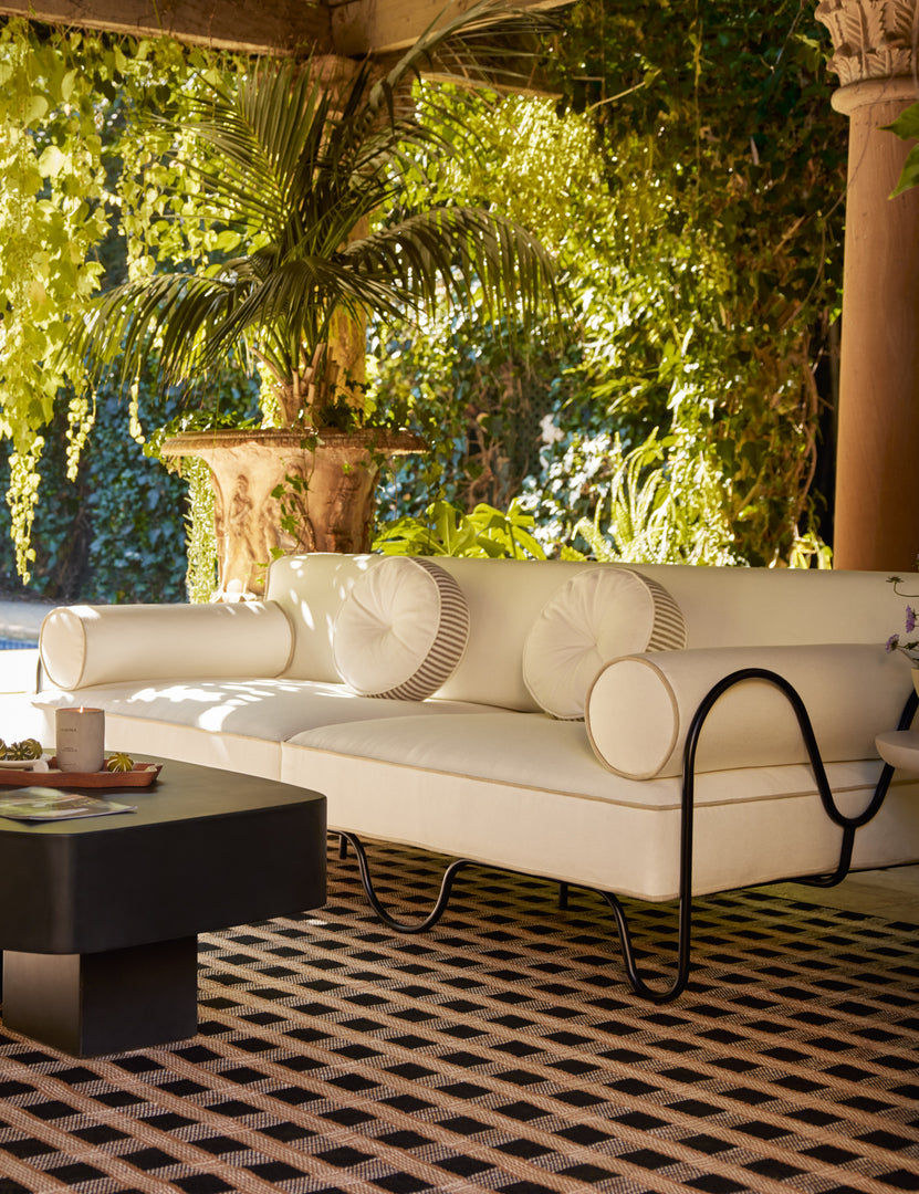 #color::ivory | Covered outdoor lounge space featuring the Peggy sculptural iron frame and white cushion outdoor sofa.