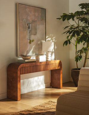 Sabal burl wood waterfall console table by Carly Cushnie styled with a sculptural table lamp and large canvas wall art.