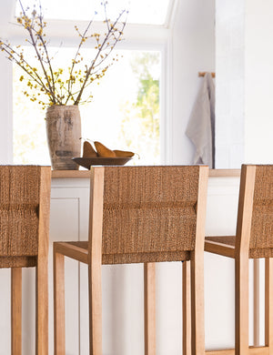Angled view of the Maritza armless light wood and woven seagrass coastal style counter stool.