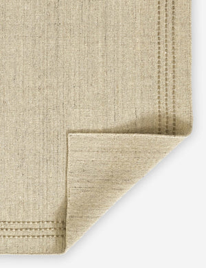 Corner of the Greco low pile wool rug with accent border stitching.