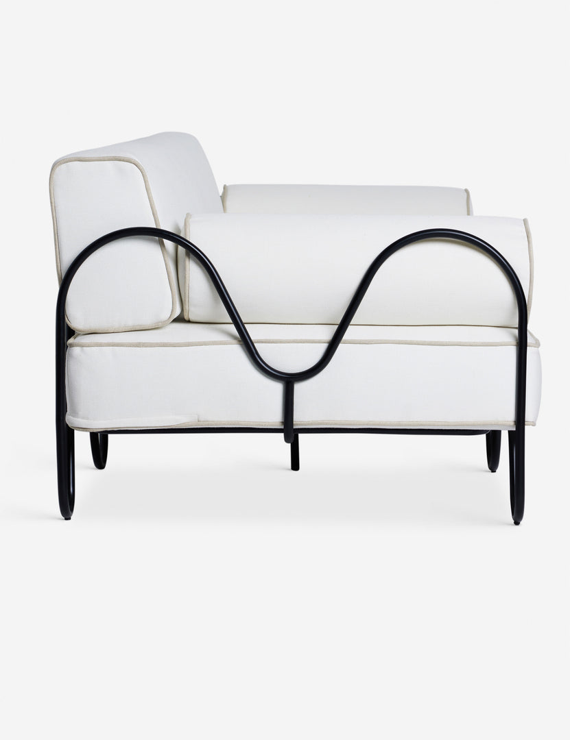 #color::ivory | Side profile of the Angled view of the Peggy sculptural iron frame and white cushion outdoor sofa.