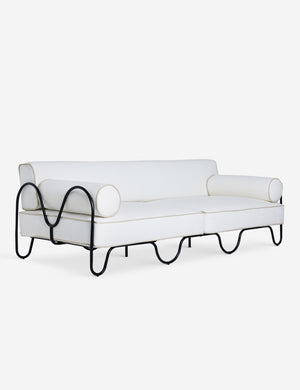 Angled view of the Peggy sculptural iron frame and white cushion outdoor sofa.
