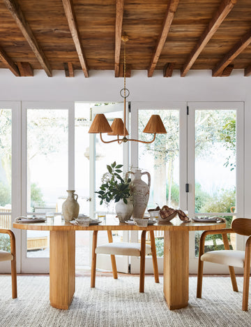 #color::natural | Elvia oval rattan stacked leg dining table with a rattan chandelier hanging above.