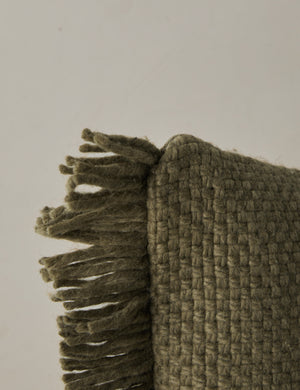 Corner of the Thorpe chunky woven fringed outdoor pillow in moss.