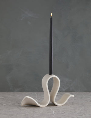 Whit white Candelabra by SIN with an undulating silhouette and a black taper candle