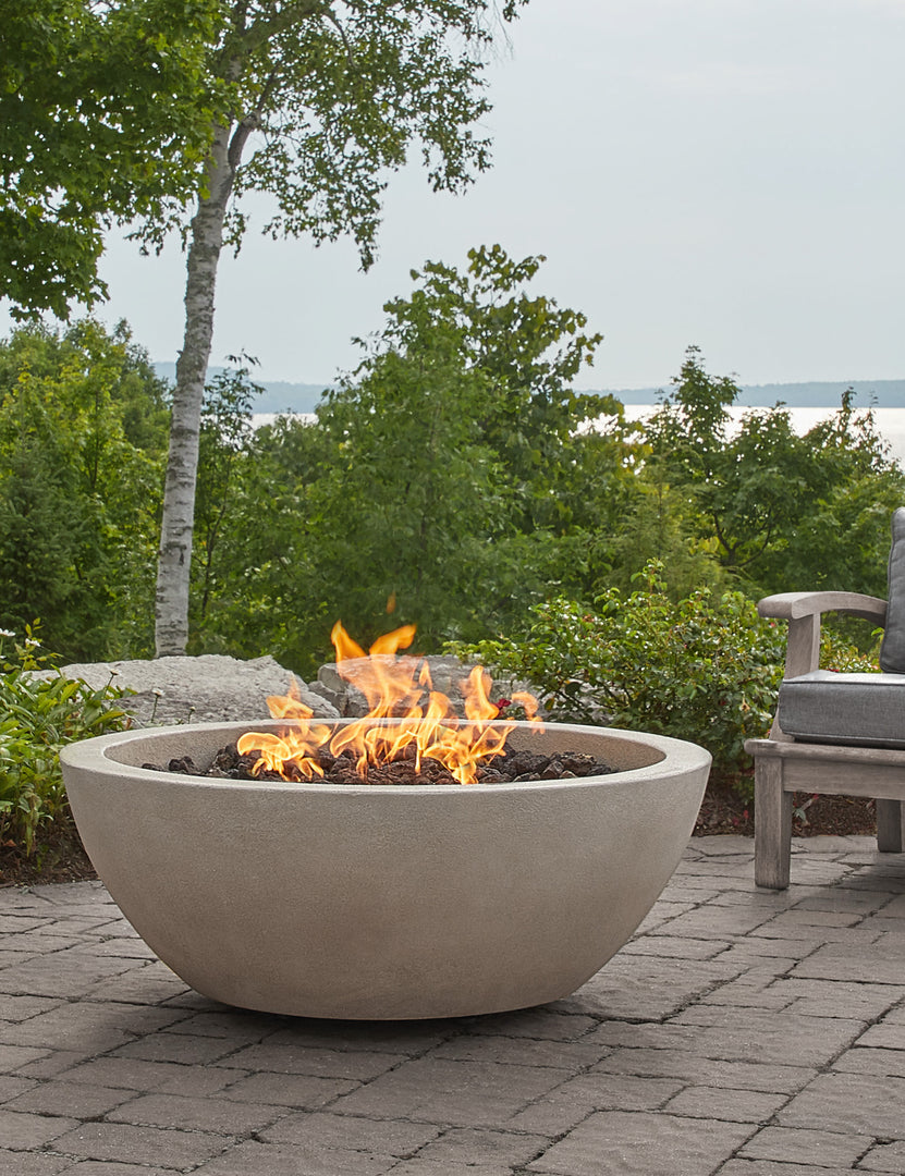 #color::fog #size::42- #configuration::propane | The Benno fog fire bowl sits in an outdoor space next to outdoor lounge furniture