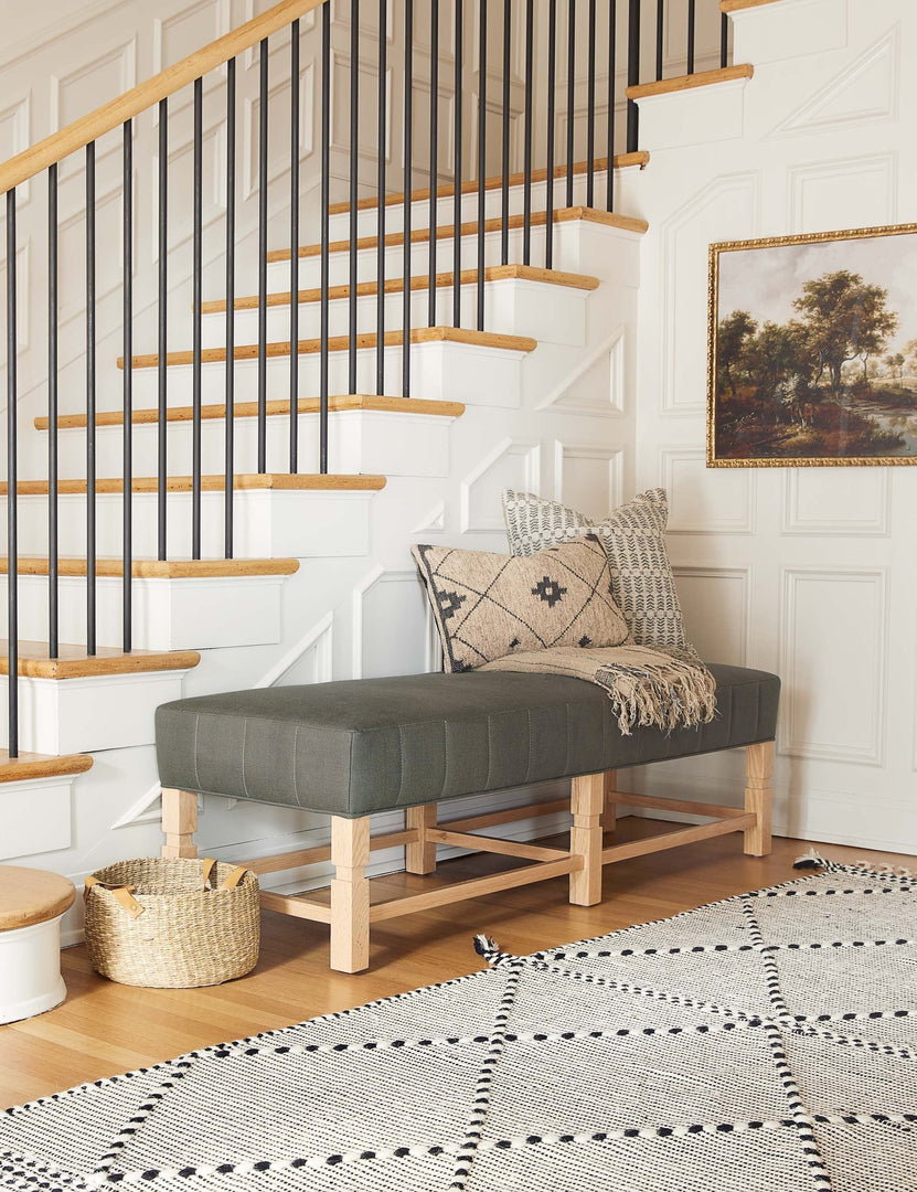 #color::loden | The ambleside loden gray linen bench sits by a staircase against white accented walls near a black and white patterned rug