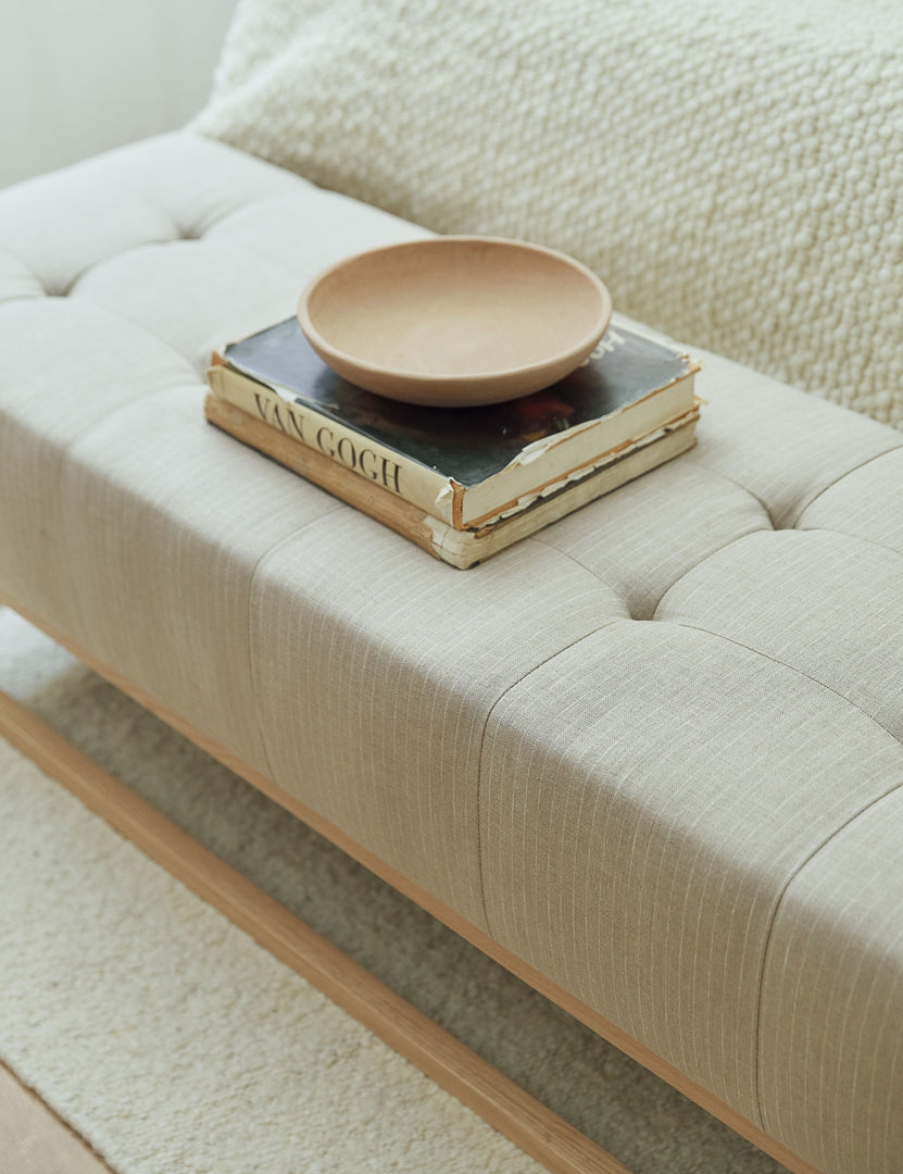 #color::stripe | The Grasmere natural stripe linen wooden bench sits at the end of a neutral-toned with a bowl and stack of books atop it