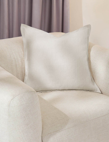 #color::ivory #style::square #fill type::with-feather-down-insert #fill type::pillow-cover-only | The arlo ivory square pillow sits in a studio room on a white linen accent chair