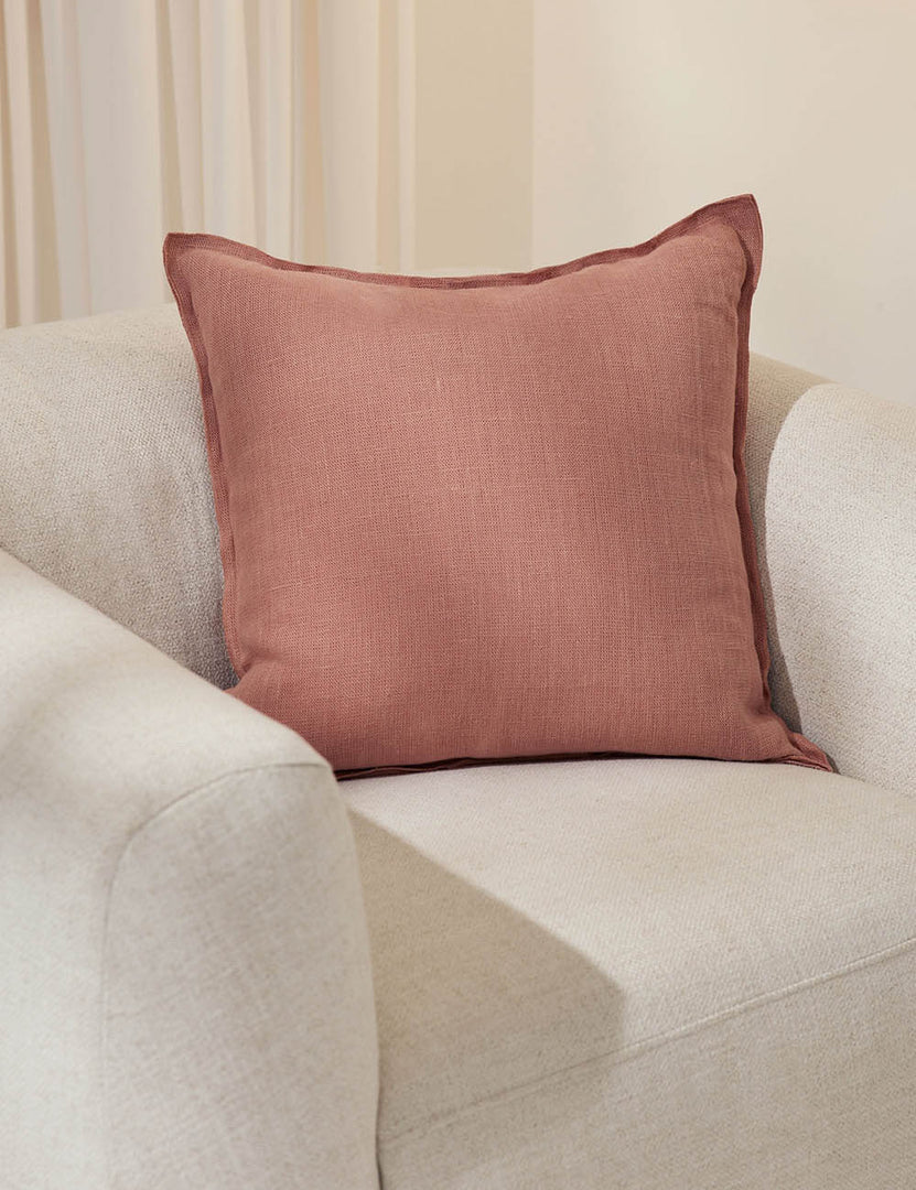 #color::terracotta #style::square #fill type::with-feather-down-insert #fill type::pillow-cover-only | The arlo terracotta square pillow sits in a studio on top of a white linen accent chair