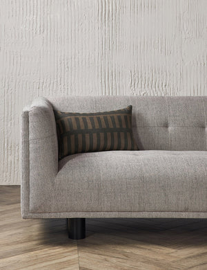 The Kellan lumbar throw pillow sits on a gray linen sofa in a studio room with hardwood floors