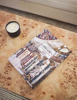 A photography book and lit candle sit on top of the Brisa rectangular burl wood coffee table with four legs