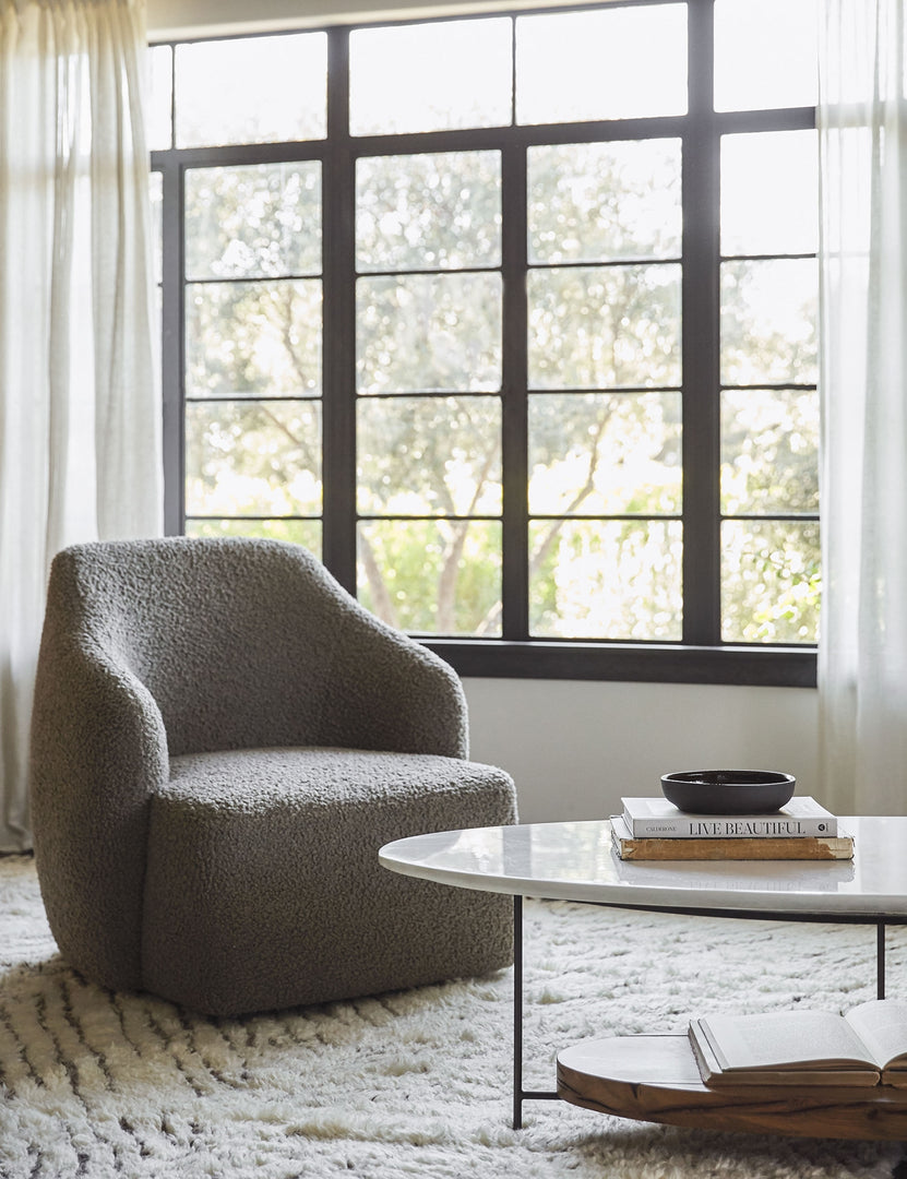 #showall::39840592068707 | The Tobi gray boucle swivel chair sits atop a plush ivory rug in front of a wall with large black-framed windows and sheet curtains