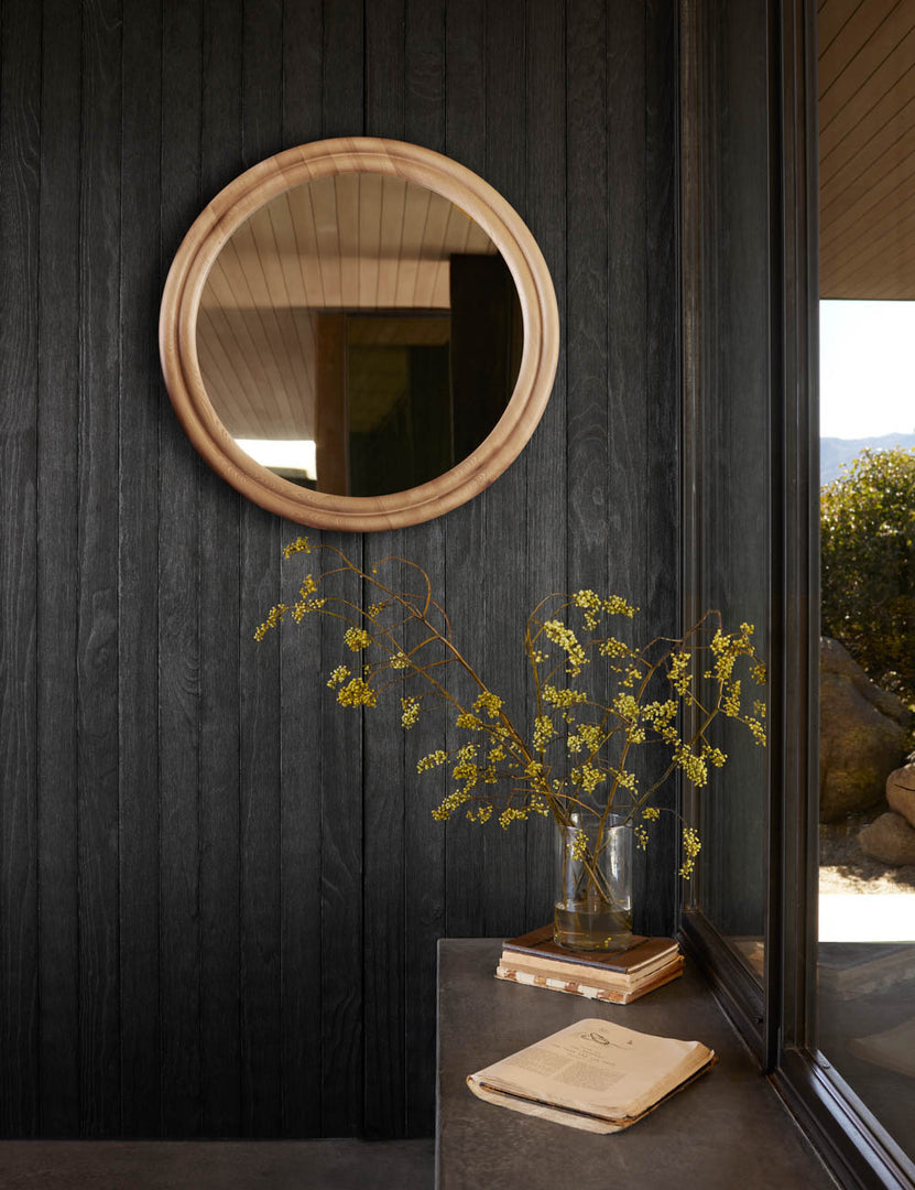 #color::natural | The Bourdon Double-Framed Natural Ash Round Mirror hangs on a black wood paneled wall