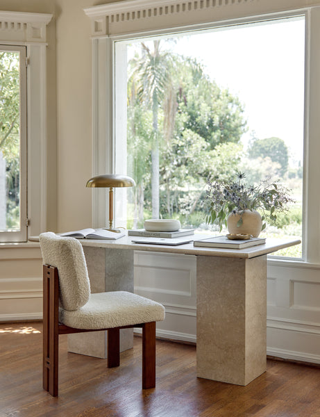 #color::cream-sherpa | Sydney Dining Chair sits next to a marble desk in a room with large accented windows and a polished brass desk lamp