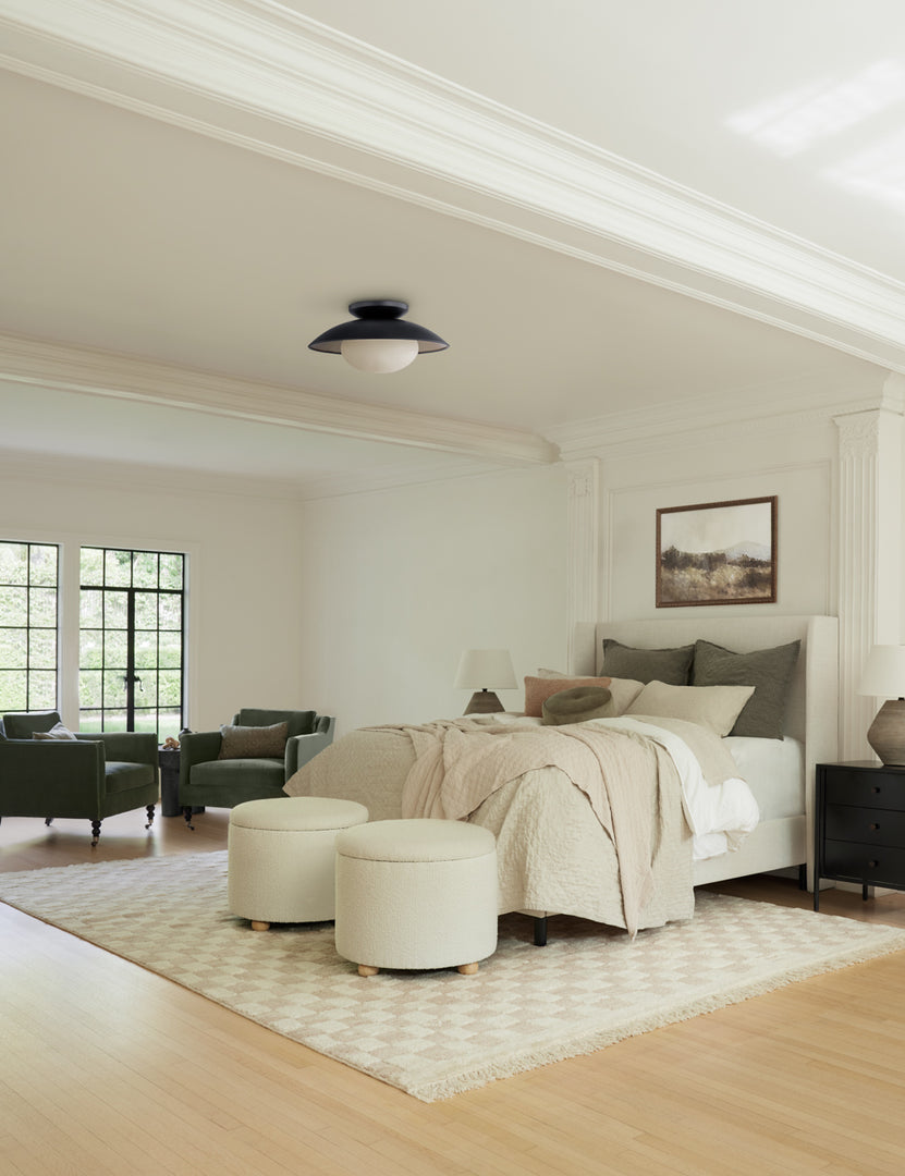 #color::white-boucle #size::24-Dia | Two Kamila White Boucle 24-inch ottomans sit at the end of a ivory linen framed bed with olive linens atop a checkerboard rug