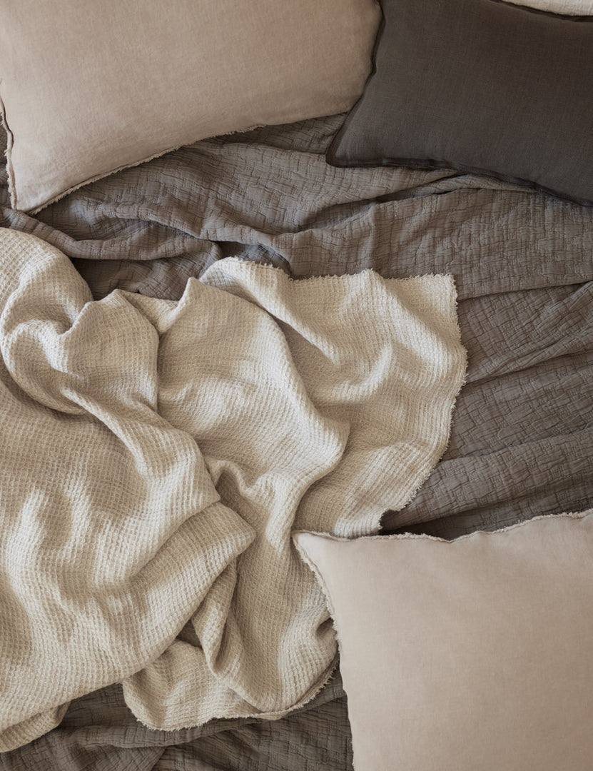 #color::pebble #size::king #size::queen #size::twin | The Ojaj pebble cotton matelassé coverlet by pom pom at home lays amongst a gray throw blanket, a dark gray sham, and lighter gray throw pillows