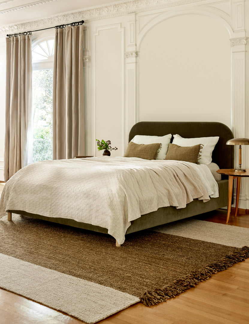 #size::queen #size::king #color::loden-velvet #size::cal-king | The Solene Loden Velvet platform bed sits atop a brown and natural rug in a room with a tall ceiling and accented walls