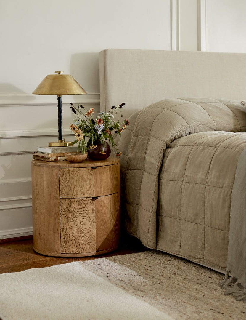 #color::natural | Kono 2-drawer round oak nightstand styled with a brass table lamp and vase with flower.s