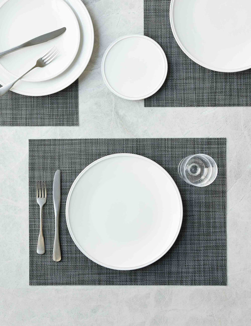 #color::cool-grey | The Set of four cool gray Mini Basketweave Rectangle Placemat by Chilewich sits under a white dinnerware set