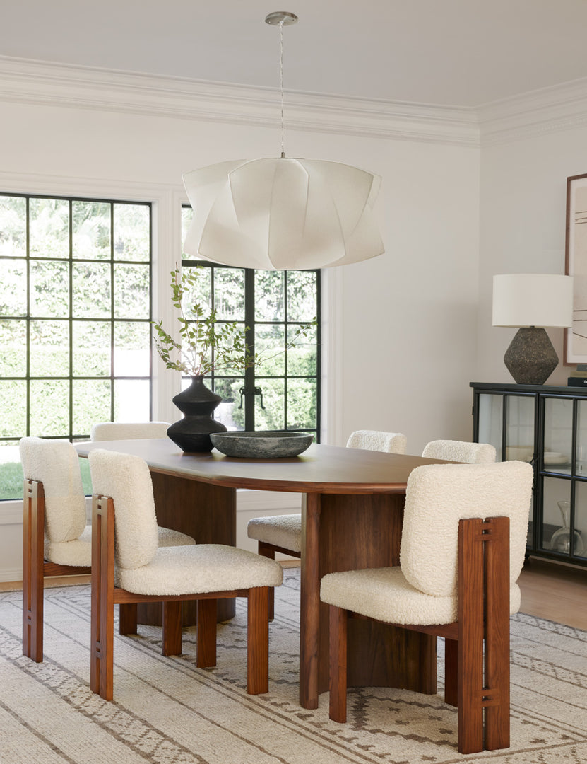 #color::cream-sherpa | Six Sydney Dining Chairs sit around an oval dining table with a black centerpiece vase beneath a geometric white chandelier 