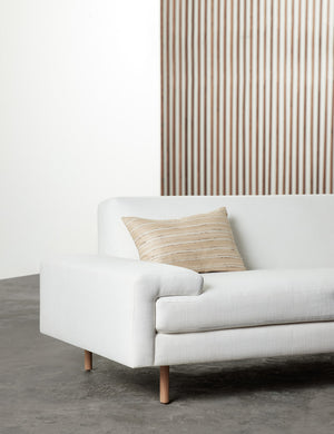 The leni lumbar silk pillow sits in a studio room on a white linen sofa