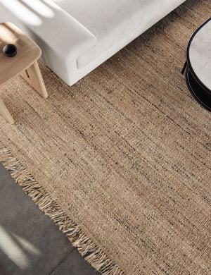 Close up of the Hagan rug laying under a wooden side table and a white sofa