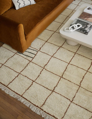 Ivory and ochre Irregular Grid Rug by Sarah Sherman Samuel lays under a conganc velvet sofa and a rounded coffee table